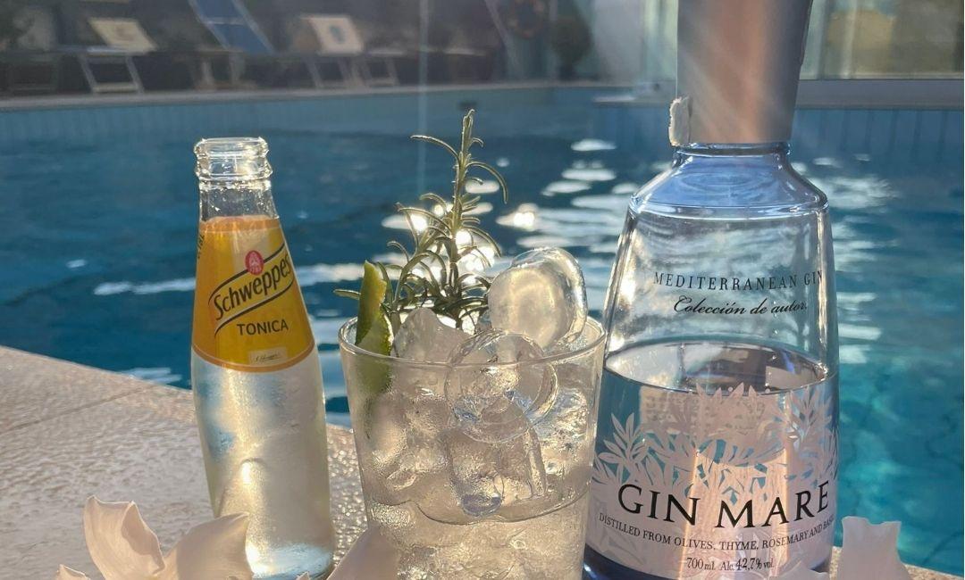 Cocktail rinfrescante a bordo piscina, sole estivo, relax e profumo di rosmarino.