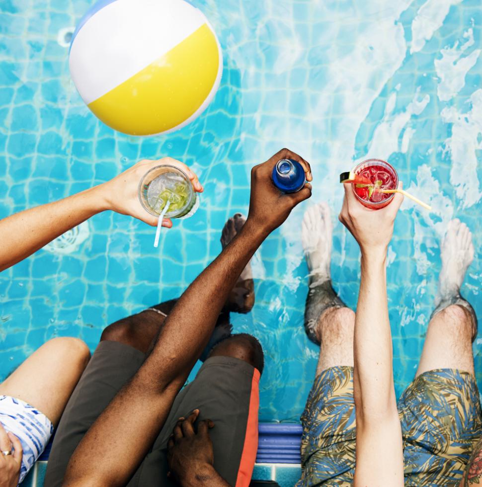 Persone rilassate con cocktail in piscina, piedi nell'acqua, atmosfera estiva e spensierata.
